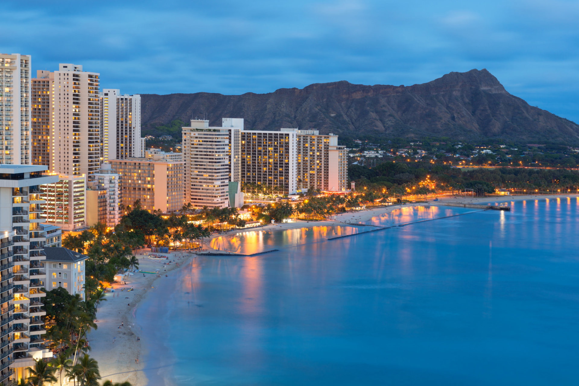 Tropical coastal city skyline beside turquoise ocean water and palm trees